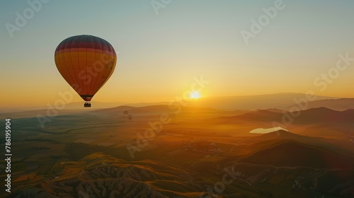 A hot air balloon ascends into the sky at dawn, carrying passengers on a breathtaking aerial journey above the scenic landscape during a hot air balloon festival event. © Abdul