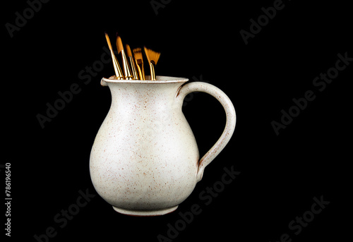 Earthenware Wine Jug with Artists Paint Brushes Isolated on a Black Background