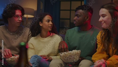 Black guy holding bowl with popcorn and telling friends joke