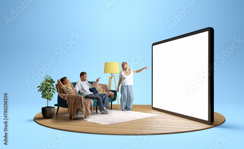 Young positive family in pajamas, man, woman and children sitting on sofa and looking at giant 3D model of tablet with empty screen. Concept of business, Internet services, travelling © master1305
