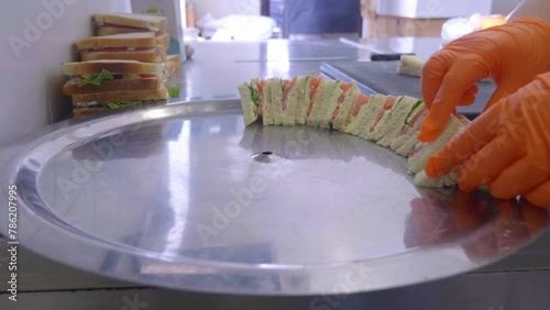 Captured from a side angle, a chef artfully arranges tramezzini on a tray, showcasing the sandwiches' elegance and readying them for service