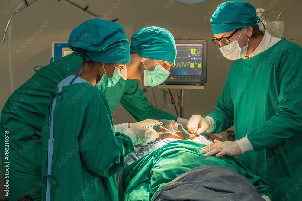 Team of surgery doctor in Operating Room, Assistant Hands out Instruments to Surgeons During Operation. doctor and nurse surgeons in green gown coat at hospital operating theater. Team of surgery doctor in Operating Room, Assistant Hands out Instruments to Surgeons During Operation. doctor and nurse surgeons in green gown coat at hospital operating theater.