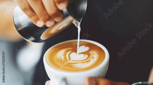 close-up of a barista's hands pouring steamed milk into a cup of coffee, creating latte art