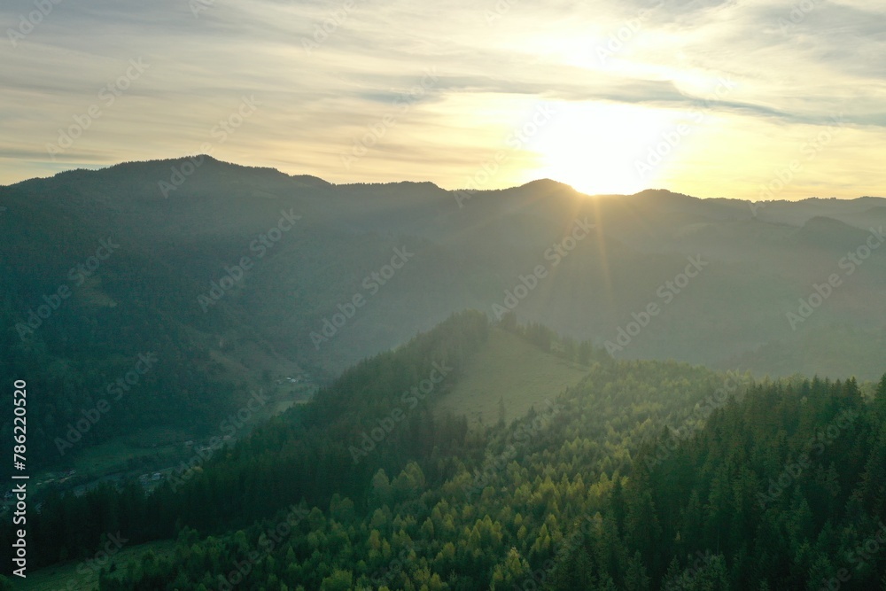 Aerial view of beautiful mountain landscape with green trees at sunrise