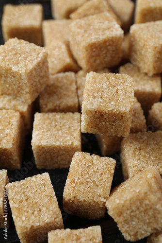 Brown sugar cubes on dark table, closeup