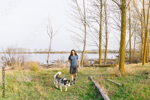 Horizontal photo leisurely walk with a husky by the river. Lifestyle concept.