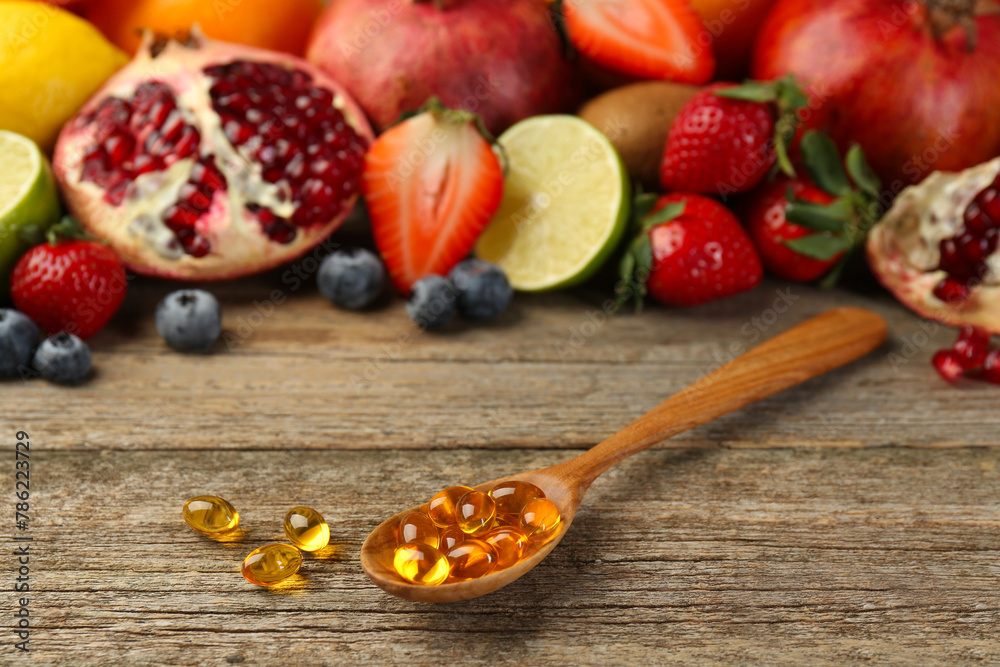 Vitamin pills in spoon and fresh fruits on wooden table Vitamin pills in spoon and fresh fruits on wooden table