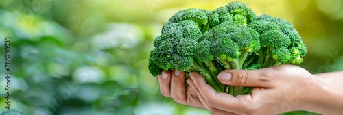 Fresh broccoli floret held with blurred background, ideal choice for text placement