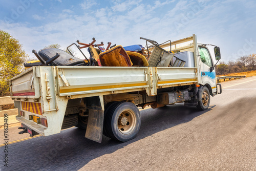 Fotografie large truck on the city street, carry used broken furniture for recycling