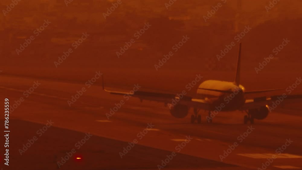 A passenger plane lands on the runway at the airport. The wheels of the airplane touch the runway and smoke appears from under them. Slow motion at sunset A passenger plane lands on the runway at the airport. The wheels of the airplane touch the runway and smoke appears from under them. Slow motion at sunset