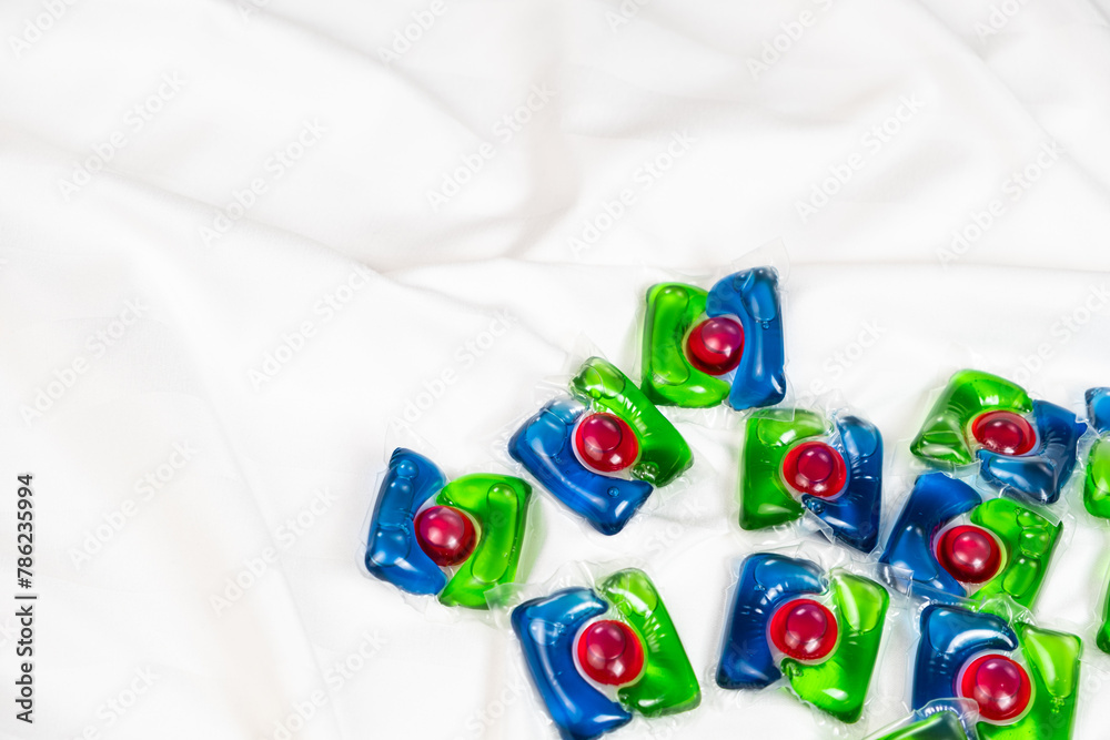 Lots of laundry pods capsule detergent on satin fabric, copy space for text.