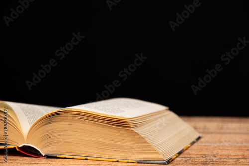 Open book on wooden and black background. The wisdom of generations, knowledge and love of reading, a place for text.