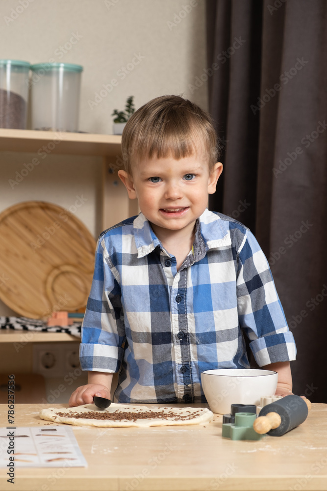 Little child sprinkling dough with flax seeds, making cookies in the kitchen. Little child sprinkling dough with flax seeds, making cookies in the kitchen.