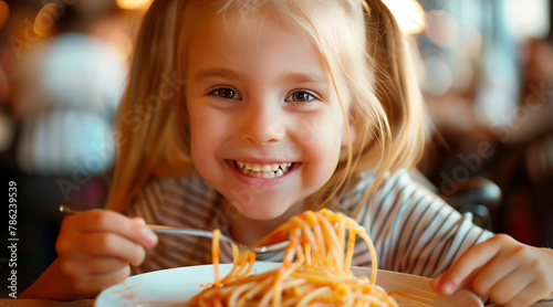 A young girl with blond hair smiling and eating spaghetti