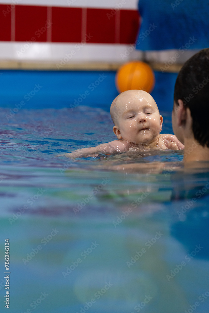 Baby with close eyes and mouth just come out of water after diving. Baby holds his breath during diving under water.