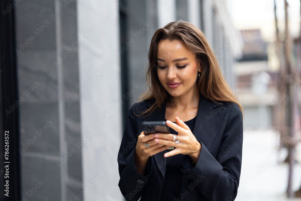 Mobile phone technology lifestyle - Hispanic business woman uses mobile phone device communicating with a colleague. Female walking outside modern office building Mobile phone technology lifestyle - Hispanic business woman uses mobile phone device communicating with a colleague. Female walking outside modern office building