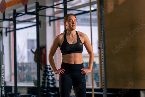 in a sports club trainer in a black top and leggings stands and poses smiling