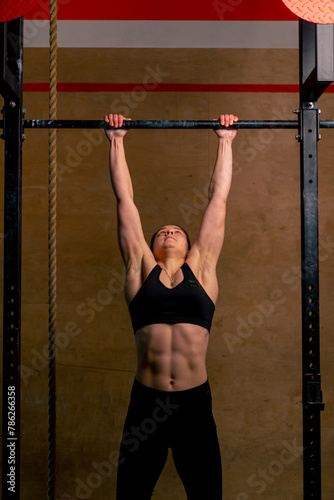 close up in the gym coach girl in black leggings and a top weighs on the horizontal bar