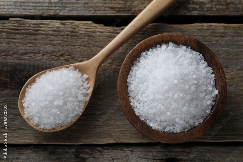 Organic salt in bowl and spoon on wooden table, flat lay Organic salt in bowl and spoon on wooden table, flat lay
