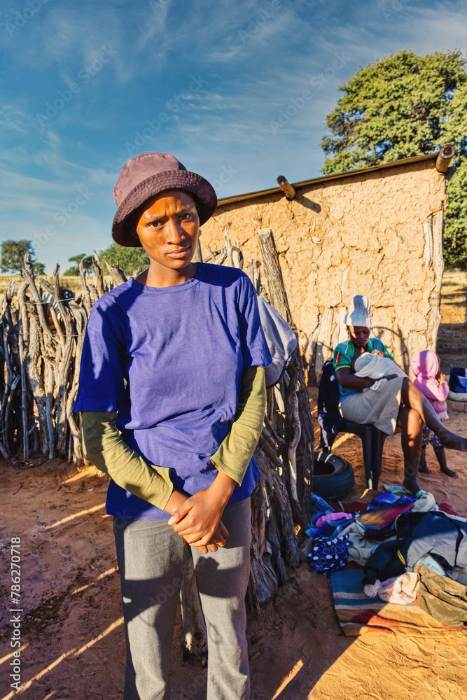 Fototapeta premium african family with one baby in the village in front of the shack, mud house in the background, ngo charity helping