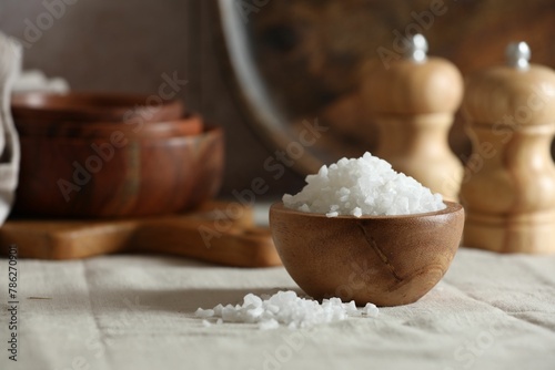 Organic salt in wooden bowl on table, closeup. Space for text