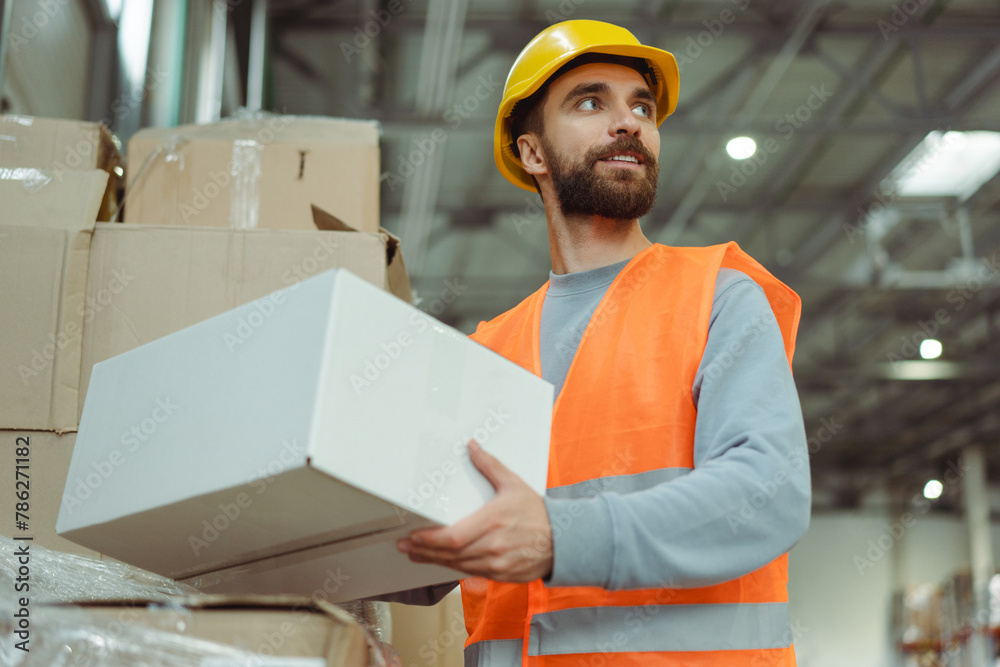 Smiling bearded man worker wearing safety helmet and work uniform holding box, carrying it, mockup Smiling bearded man worker wearing safety helmet and work uniform holding box, carrying it, mockup