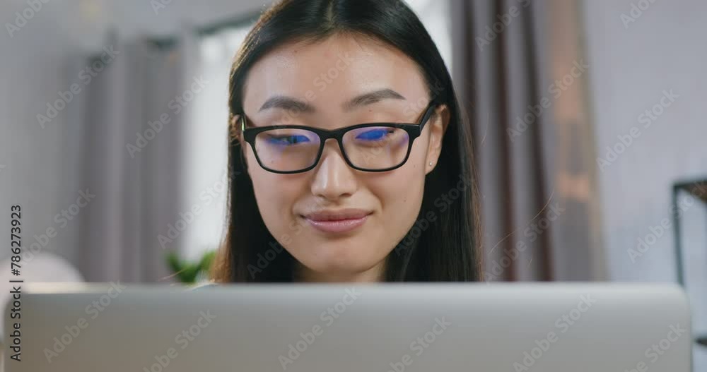 Close up portrait of young woman in glasses working on computer at home over her startup project. View over laptop. Close up portrait of young woman in glasses working on computer at home over her startup project. View over laptop.