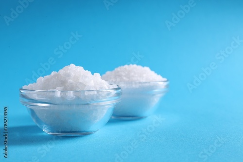 Natural salt and bowls on light blue background. Space for text