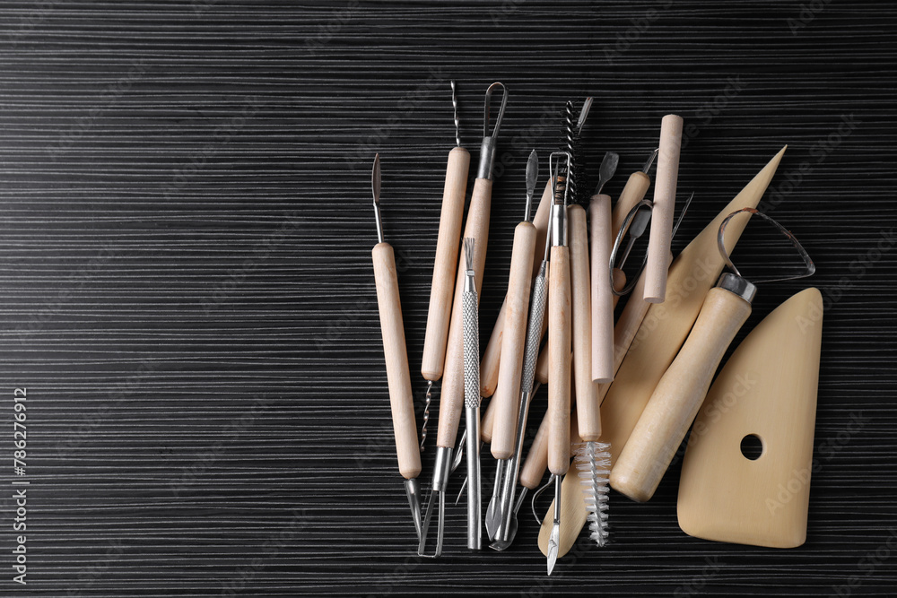 Clay and set of modeling tools on dark gray wooden table, flat lay. Space for text Clay and set of modeling tools on dark gray wooden table, flat lay. Space for text