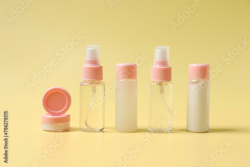 Cosmetic travel kit. Small containers of personal care products on yellow background