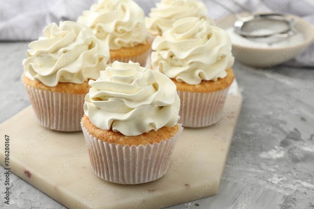 Tasty cupcakes with vanilla cream on grey table, closeup Tasty cupcakes with vanilla cream on grey table, closeup