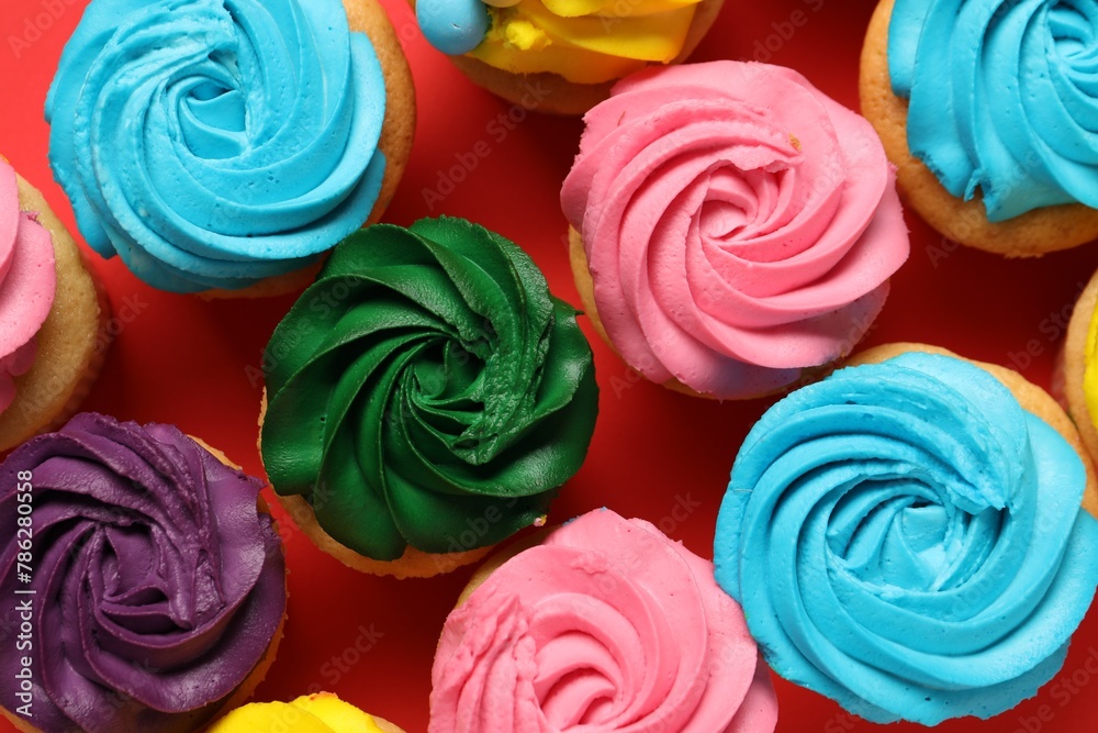 Delicious cupcakes with bright cream on red background, flat lay