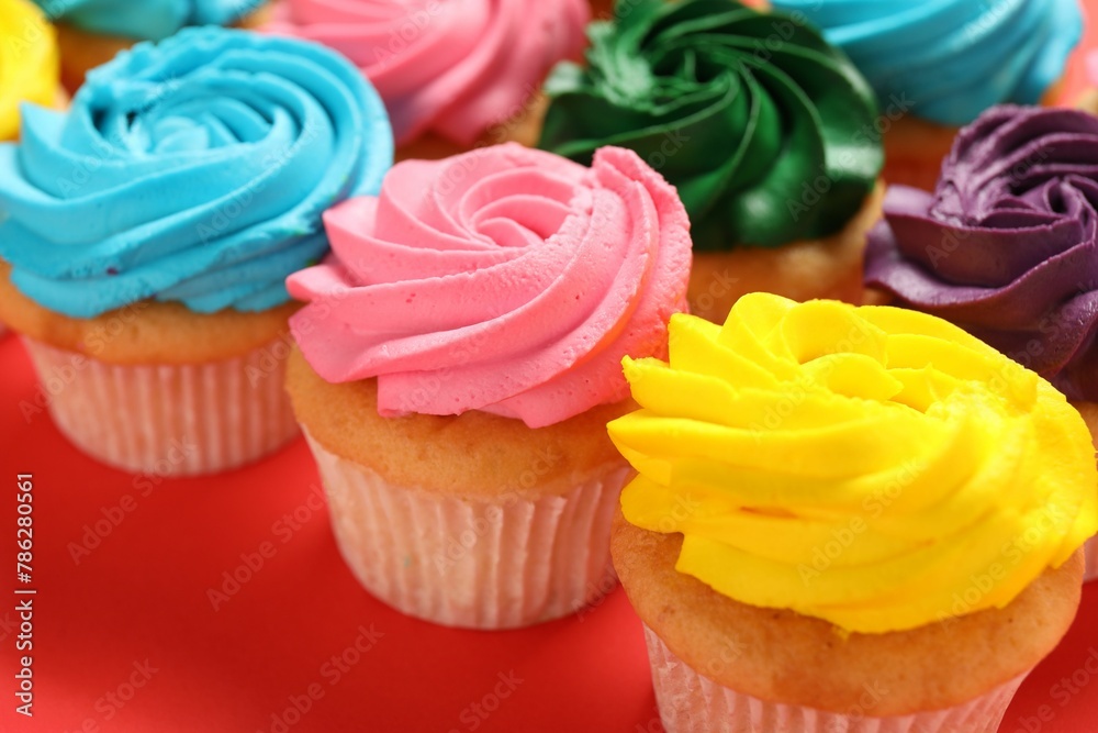 Delicious cupcakes with bright cream on red background, closeup