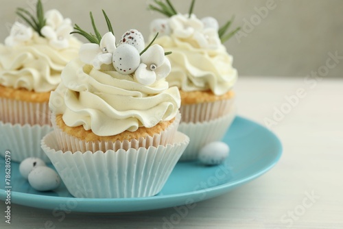 Tasty Easter cupcakes with vanilla cream on light wooden table, closeup