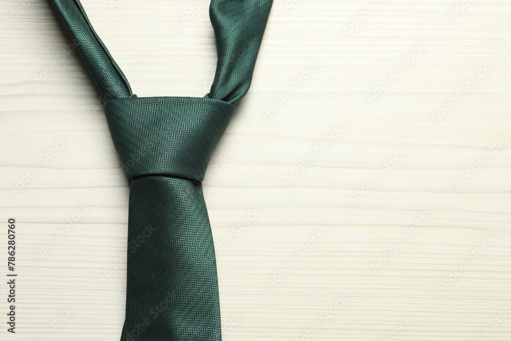 One green necktie on white wooden table, top view. Space for text One green necktie on white wooden table, top view. Space for text
