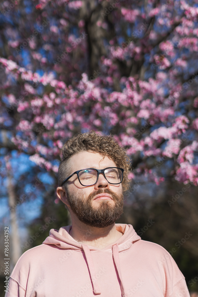 Man allergic enjoying after treatment from seasonal allergy at spring. Portrait of happy bearded man smiling in front of blossom tree at springtime. Spring blooming and allergy concept. Copy space Man allergic enjoying after treatment from seasonal allergy at spring. Portrait of happy bearded man smiling in front of blossom tree at springtime. Spring blooming and allergy concept. Copy space