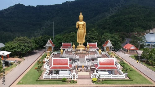 Aerial view drone shot of the A golden buddha statue on the mountain top at Hat Yai municipality public park, Songkhla Province, Thailand photo