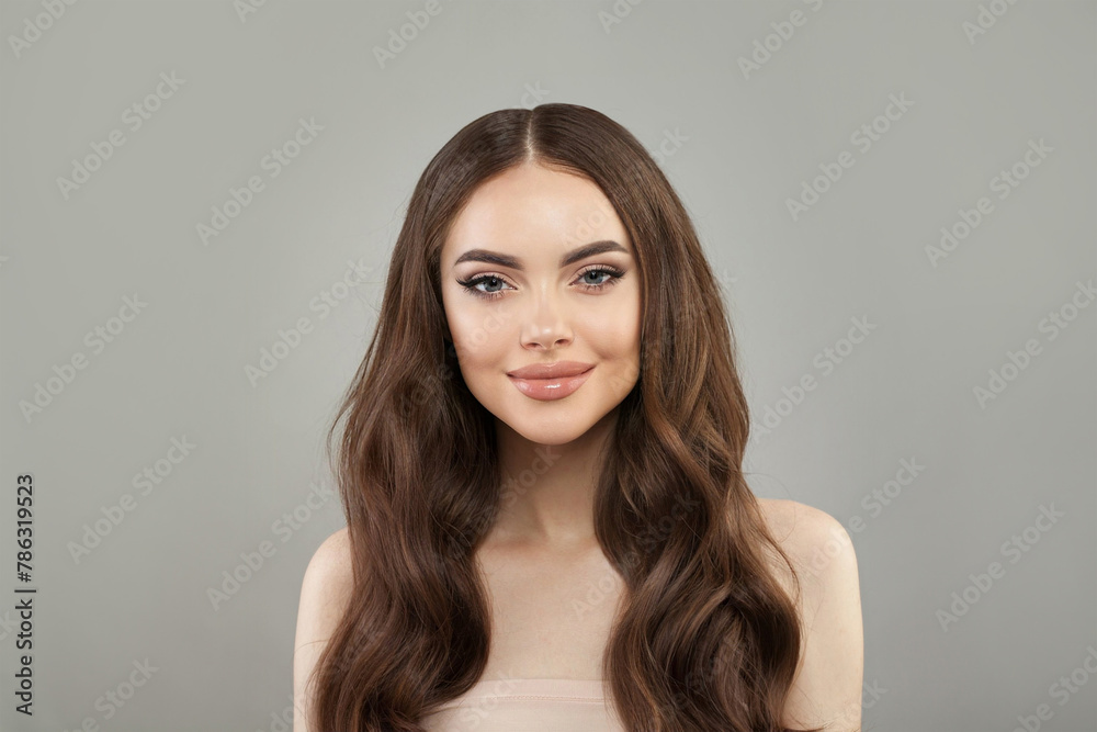 Pretty young happy woman model with natural make-up, clean healthy fresh skin and long hair posing on white background. Curly, haircare, skincare and facial treatment concept