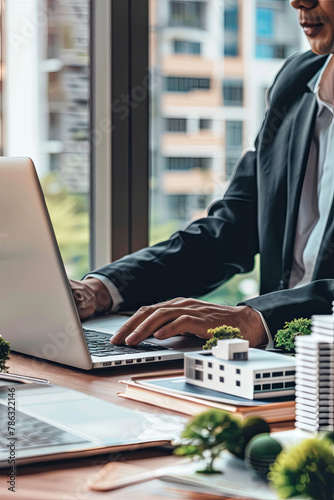 real estate business, housing development, property management. businessman working on laptop in office with building models on table. banner with copy space photo