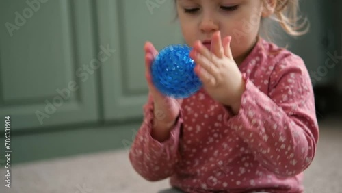 Cute baby girl playing tactile knobby balls. Young child hand plays sensory massage ball. Enhance the cognitive, physical process. Brain development. Support for Children with ADHD, autism, fidgeting. photo