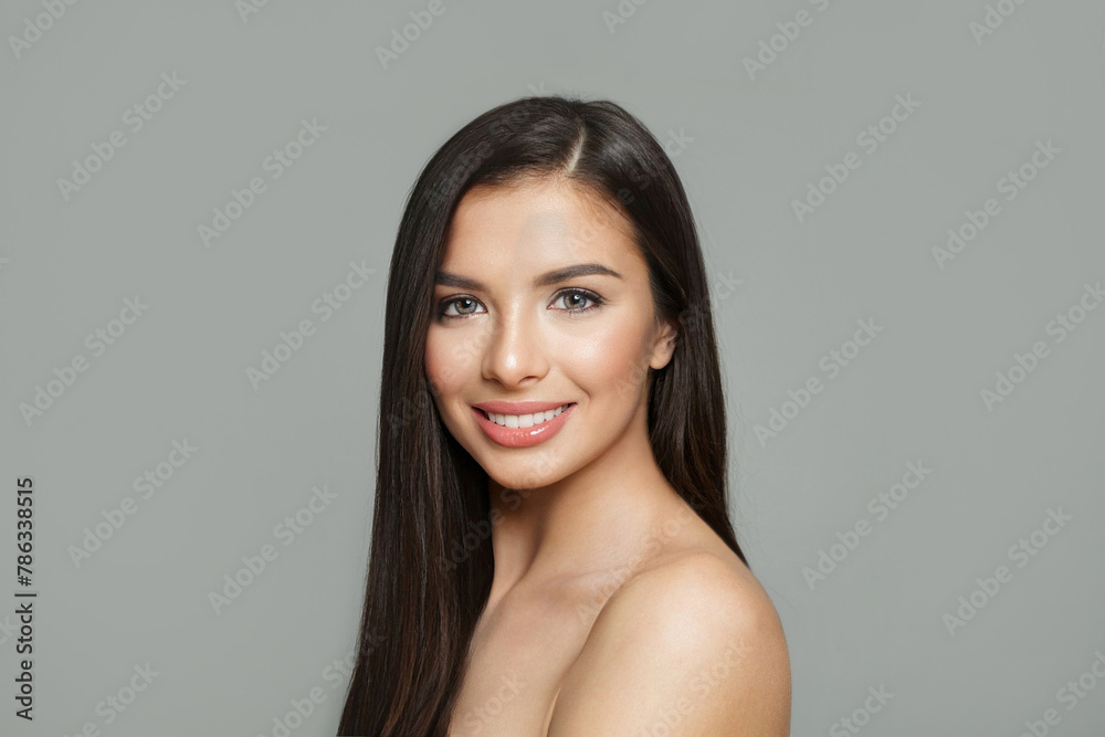 Healthy young female model with healthy hair, makeup and shiny clear skin posing against gray studio wall background. Facial treatment, cosmetology, hair care and beauty woman concept Healthy young female model with healthy hair, makeup and shiny clear skin posing against gray studio wall background. Facial treatment, cosmetology, hair care and beauty woman concept