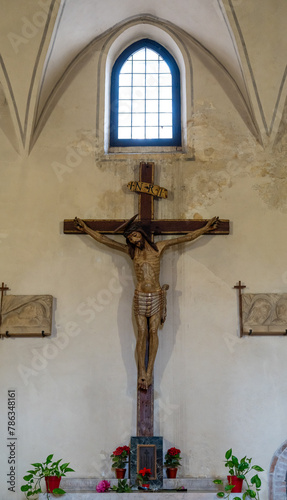 Big crucific decorating humble altar inside ancient italian church