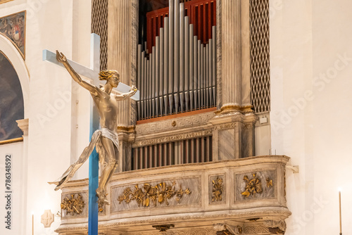 Metal pipe organ and crucifix inside church in Italy