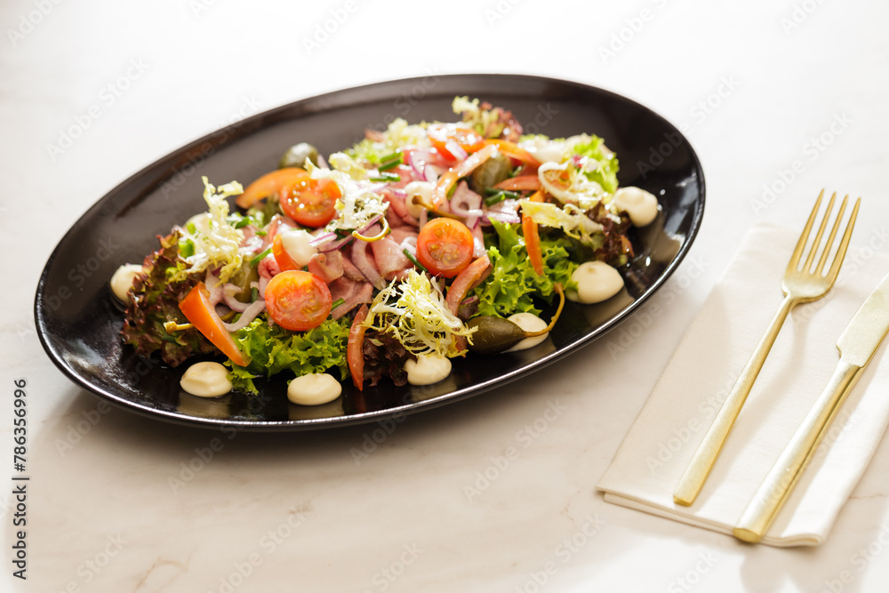 Fresh Vegetable green salad with sauce on a black plate Fresh Vegetable green salad with sauce on a black plate
