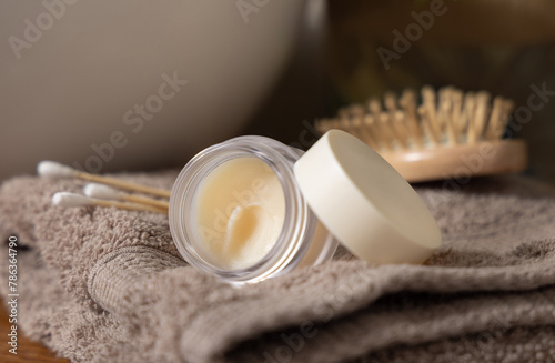 Opened Lip balm jar with blank lid on beige folded towels near basin in bath, Cosmetic mockup
