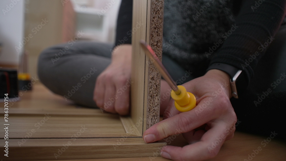 Obraz premium Close-up hand putting together furniture, DIY setup. Person placing two pieces of wood together. moving to new home concept