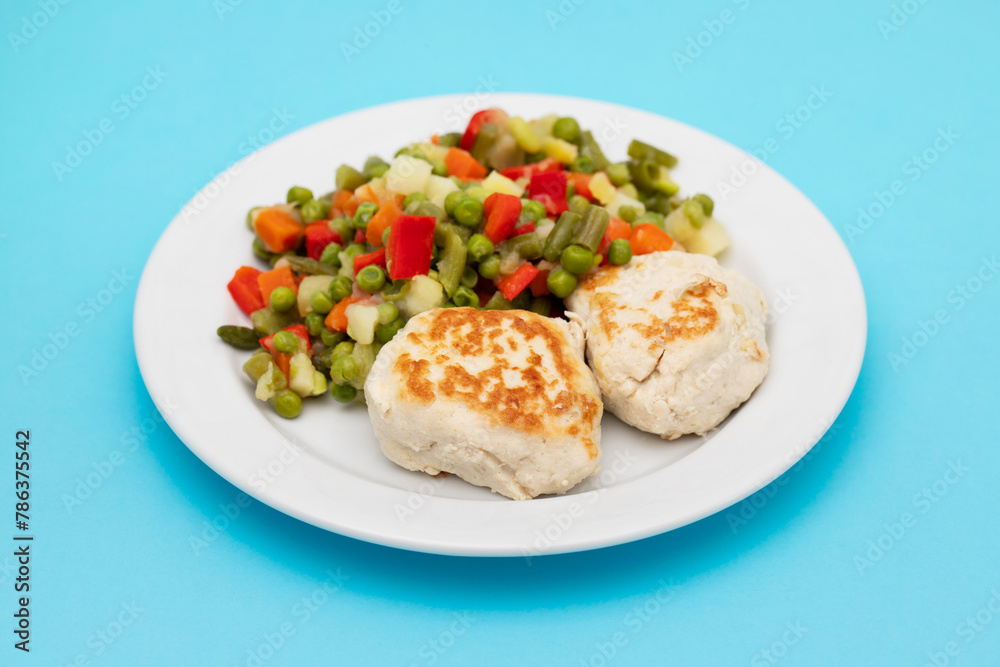 Roasted chicken cutlets with vegetables on white plate