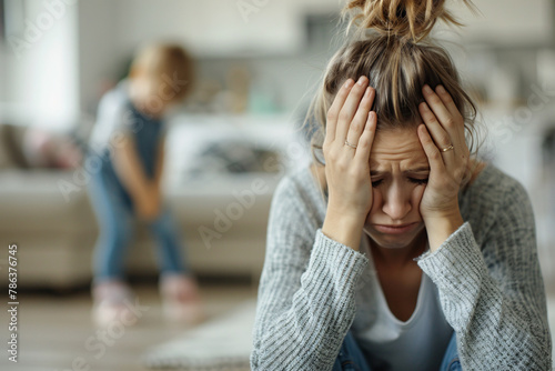 Stressed and frustrated young mother with toddler child in blurry background