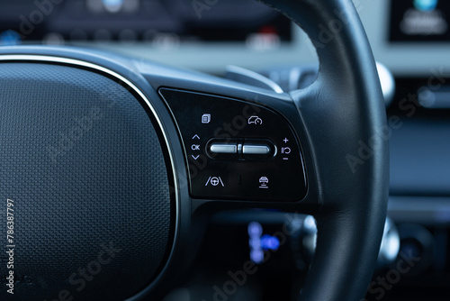 Close up of steering wheel of a new electric vehicle. Electric car control devices. Cruise control buttons, speed limitation, car's signal