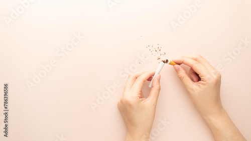 World no tobacco day. Woman hands holding broken cigarette on brown background. Stop smoking and quit smoking cigarettes concept.